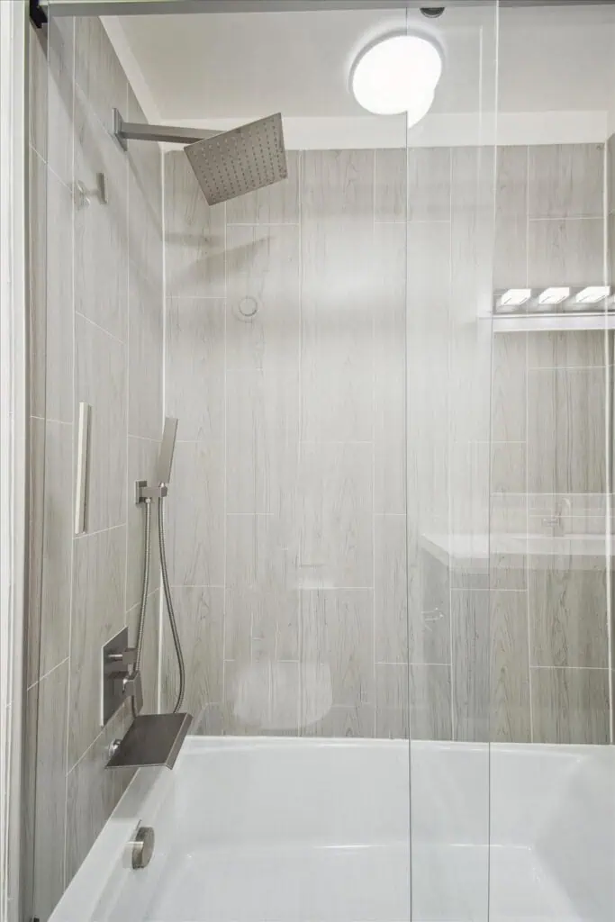 Modern shower with glass doors and gray tiles.