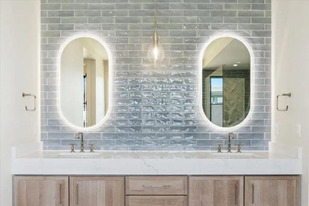 Modern bathroom with dual sinks and oval mirrors.