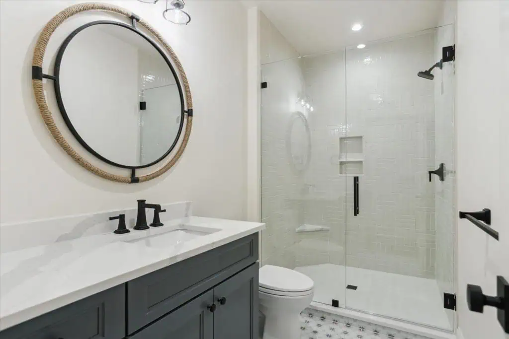 Modern bathroom with glass shower and round mirror.