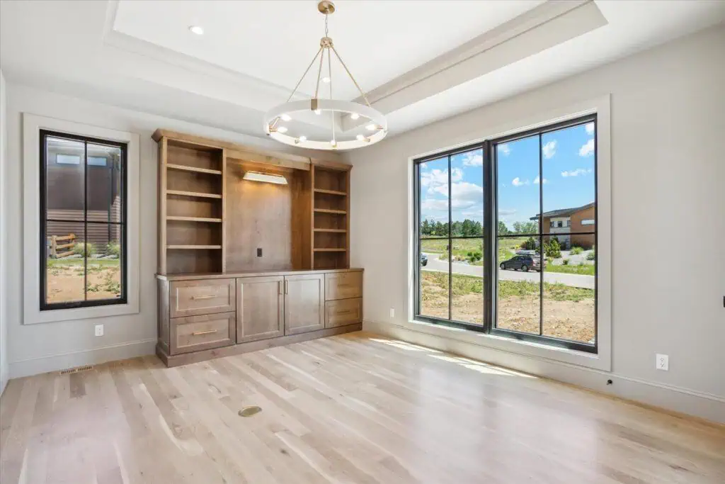 Empty room with large windows and wooden shelves.