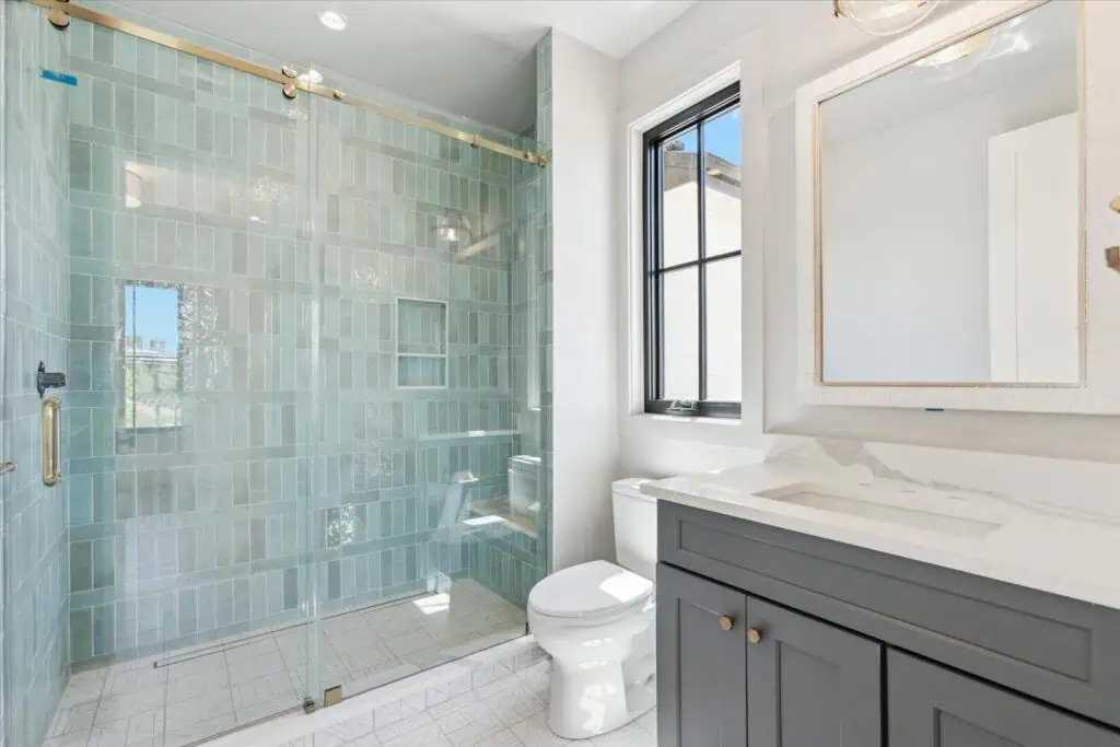Modern bathroom with glass shower and gray vanity.