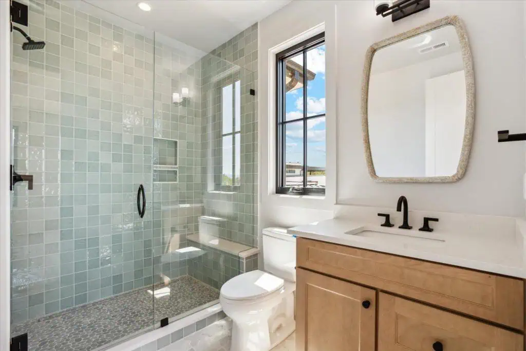 Modern bathroom with glass shower and wooden vanity.