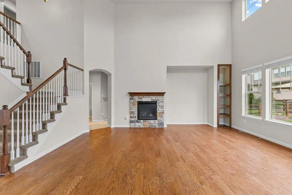 Spacious living room with fireplace and staircase.
