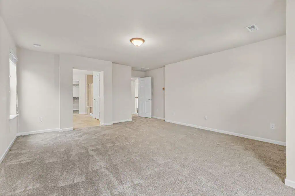 Spacious empty room with beige carpet and light walls.
