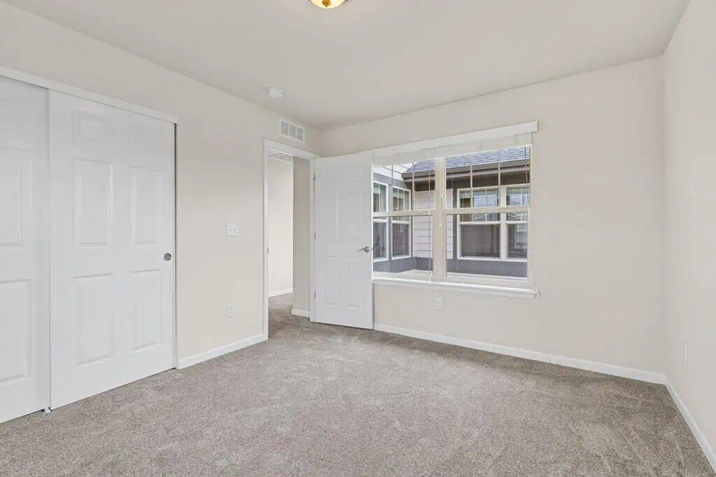 Empty bedroom with carpet and large window.