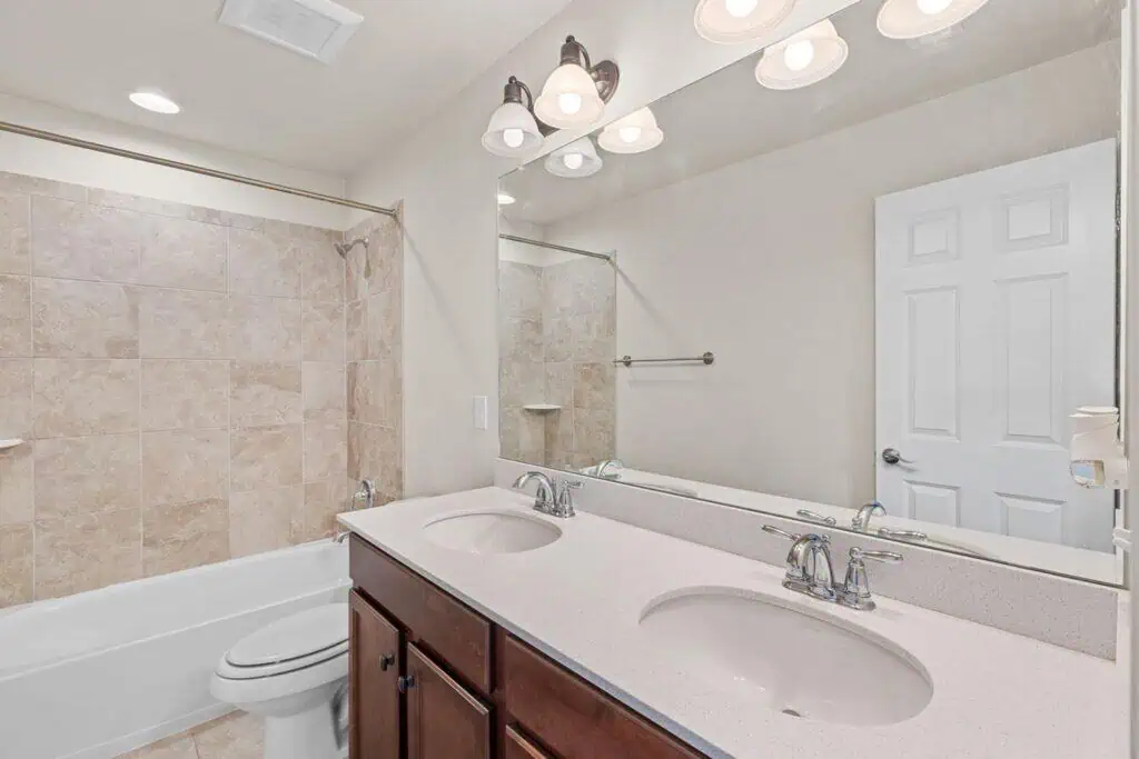 Modern bathroom with double sink and tiled bathtub.