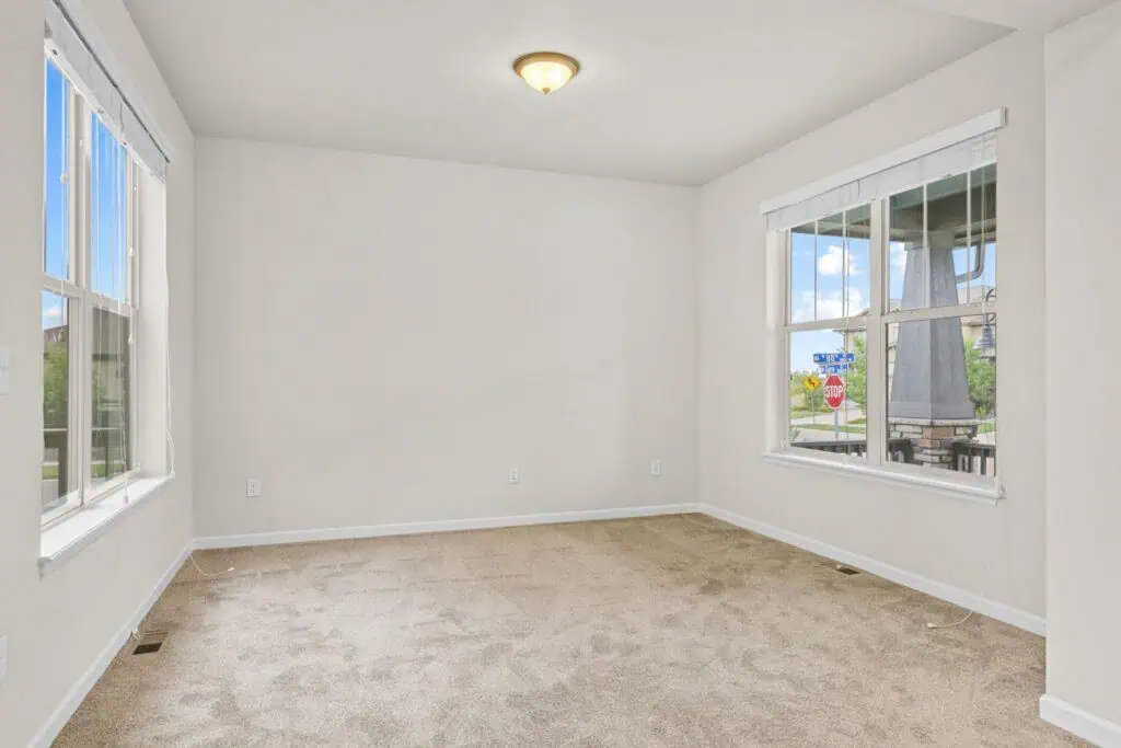 Empty carpeted room with large windows and light.