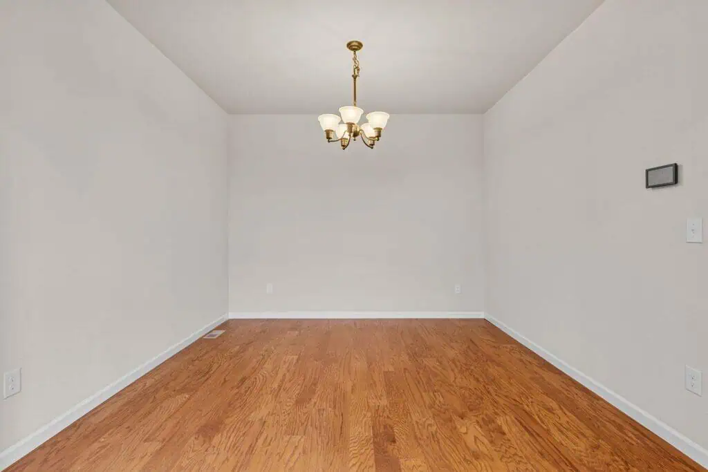 Empty room with wooden floor and chandelier.